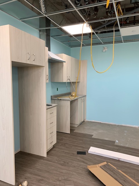 Image shows the kitchen at the Danforth location in an unfinished state. There are wires hanging from the ceiling and empty space in front of cabinets.