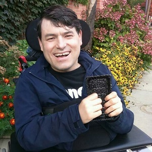 A man wearing a navy sweater is holding up a black container.