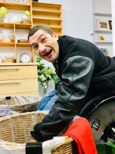 A participant sorting clothes in wicker baskets. He's smiling at the camera.