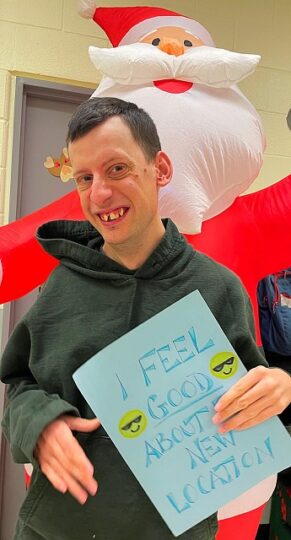 Image showing a participant holding up a blue sign. The sign reads "I feel good about our new location!"