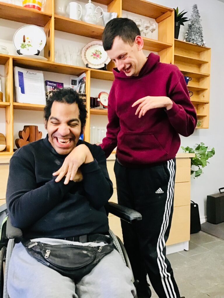 Two participants smiling while volunteering in The Pegasus Shoppe.