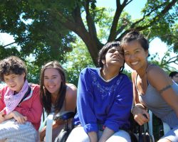 Two staff and two participants smiling in front of trees.