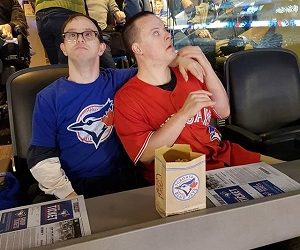 Two Pegasus participants leaning on one another at a baseball game